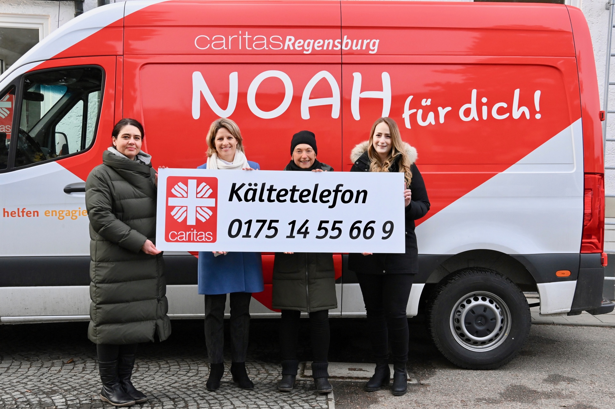 Personen vor einem roten Bus mit Schild in der Hand