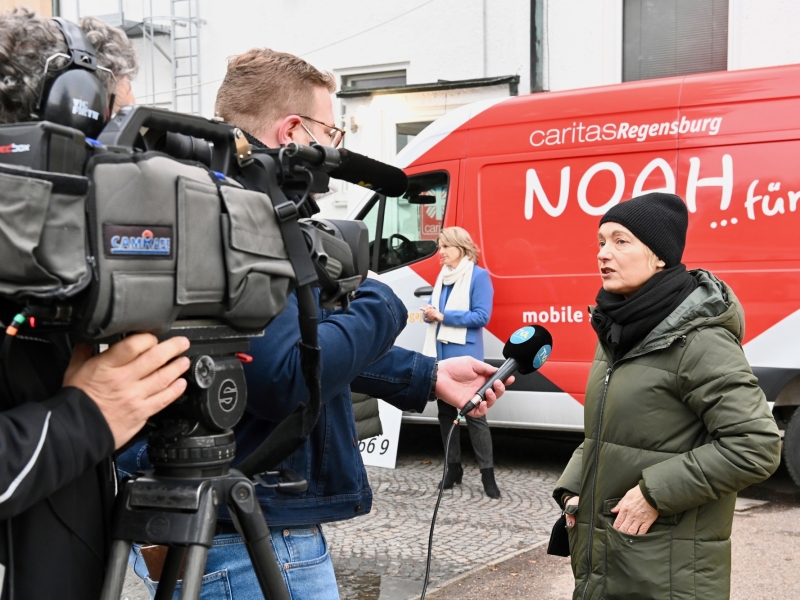 Person vor einem roten Bus im Interview