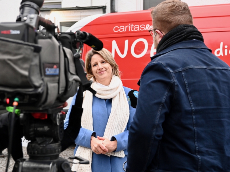 Person vor einem roten Bus im Interview