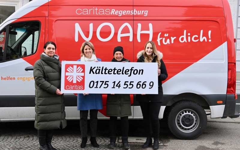 Personen vor einem roten Bus mit Schild in der Hand
