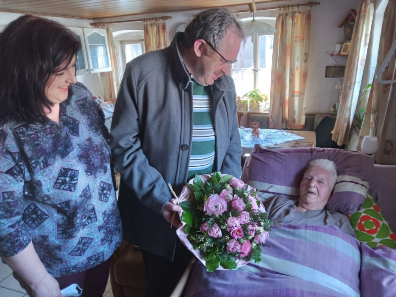 Zwei Presonen &uuml;berbringen Blumen an Seniorin