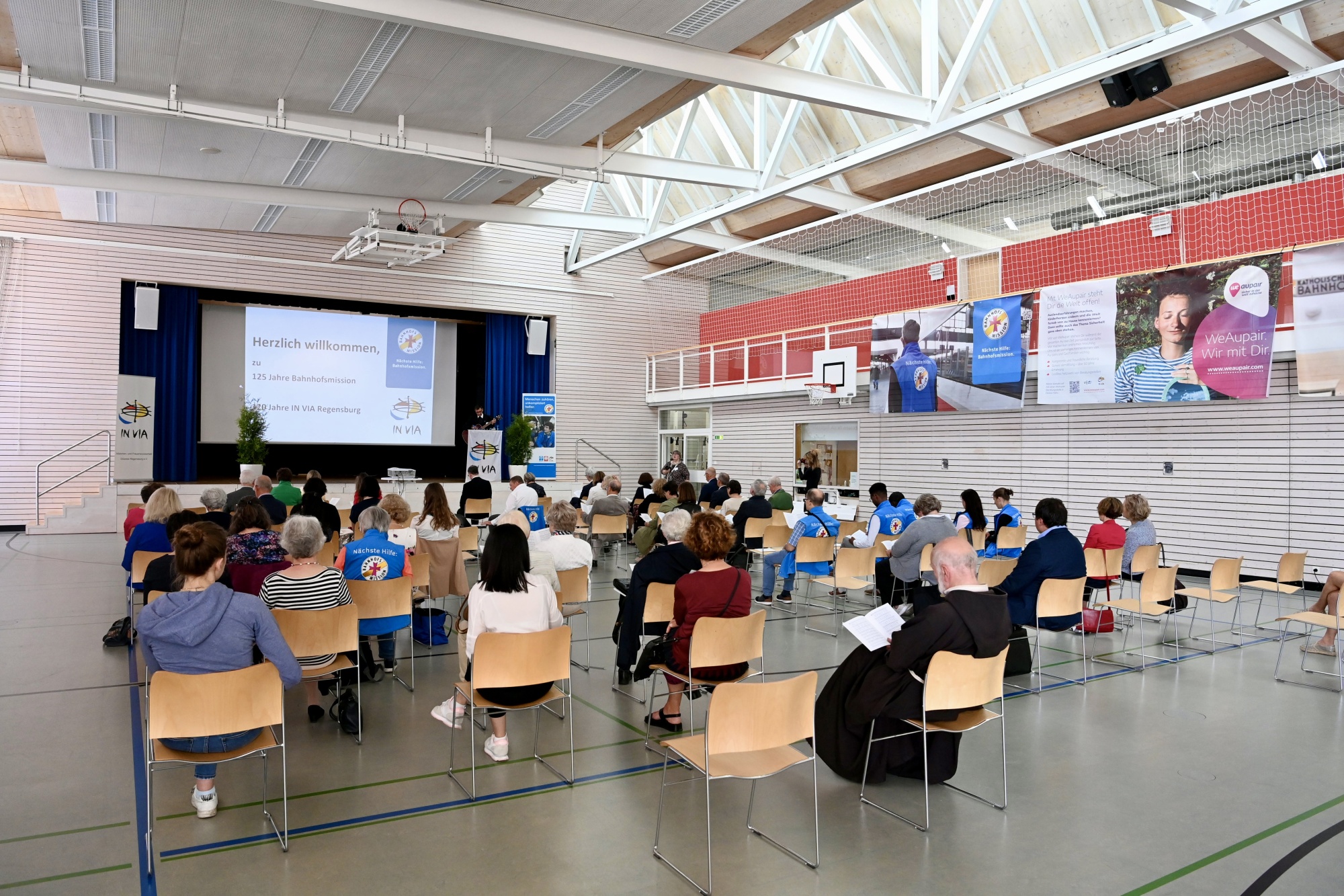 Turnhalle mit Personen die auf Monitor sehen