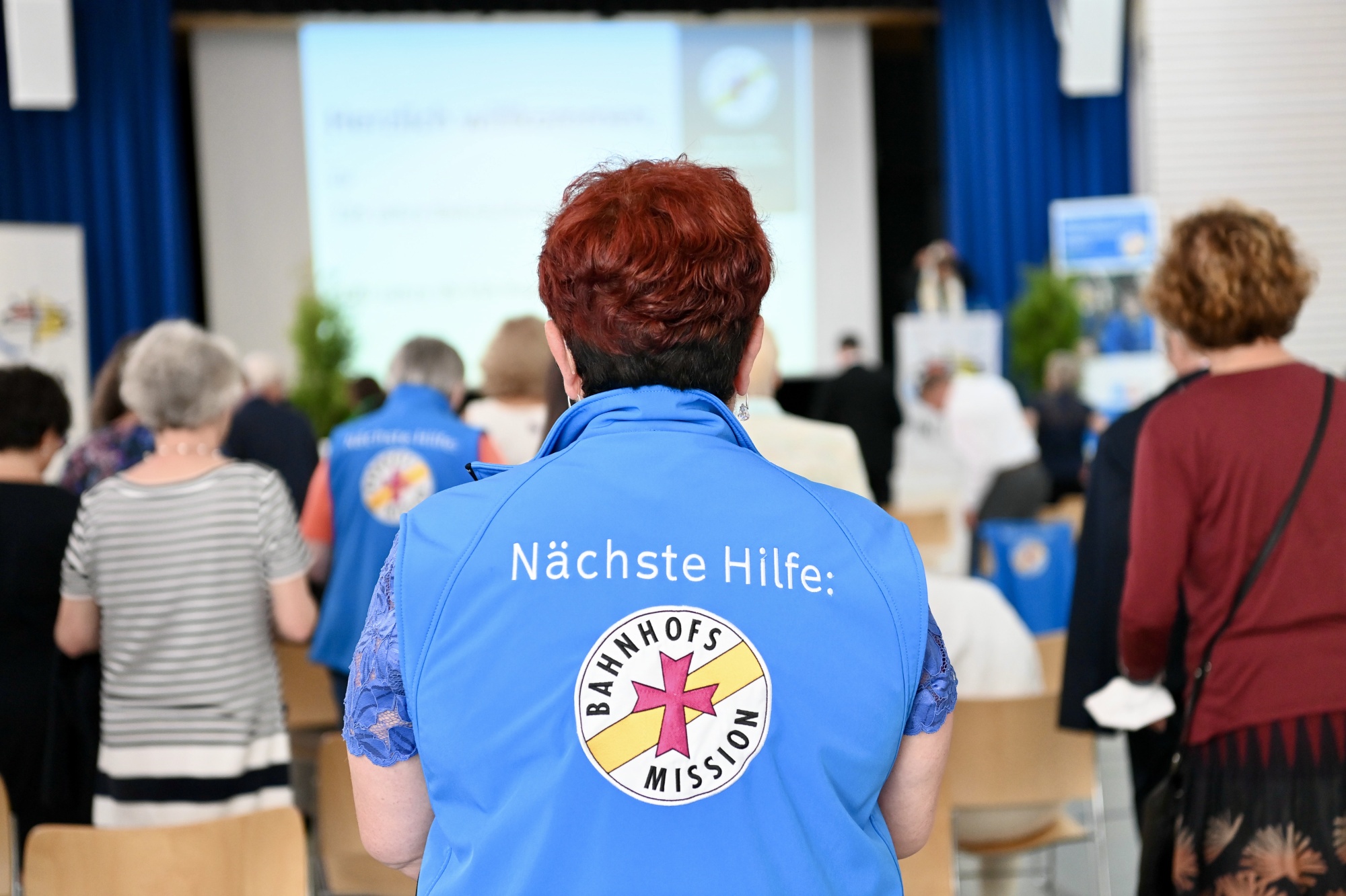 Turnhalle mit Personen die auf Monitor sehen