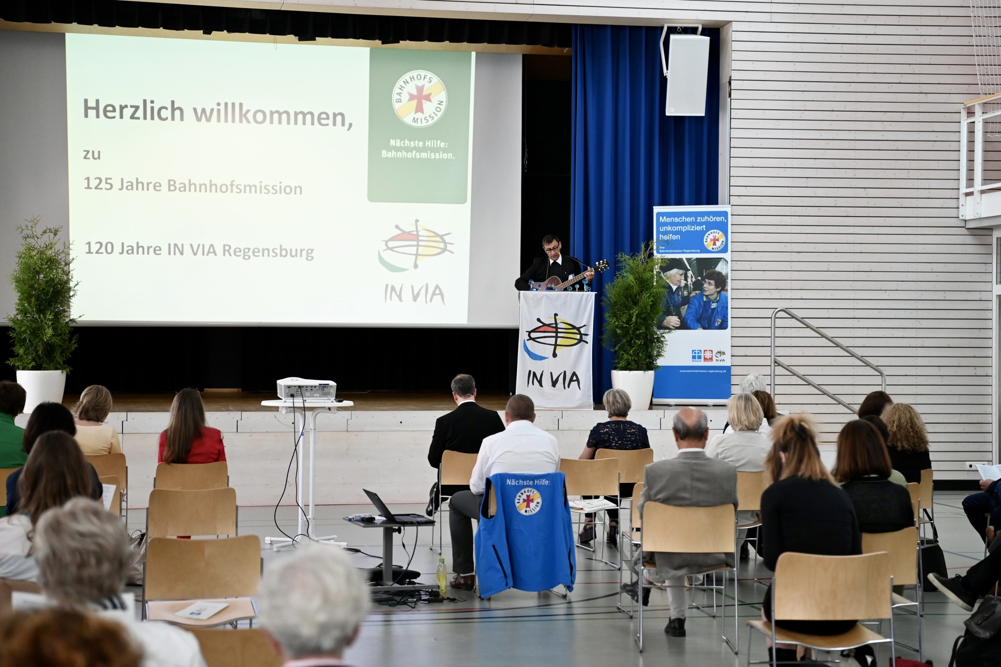 Turnhalle mit Personen die auf Monitor sehen