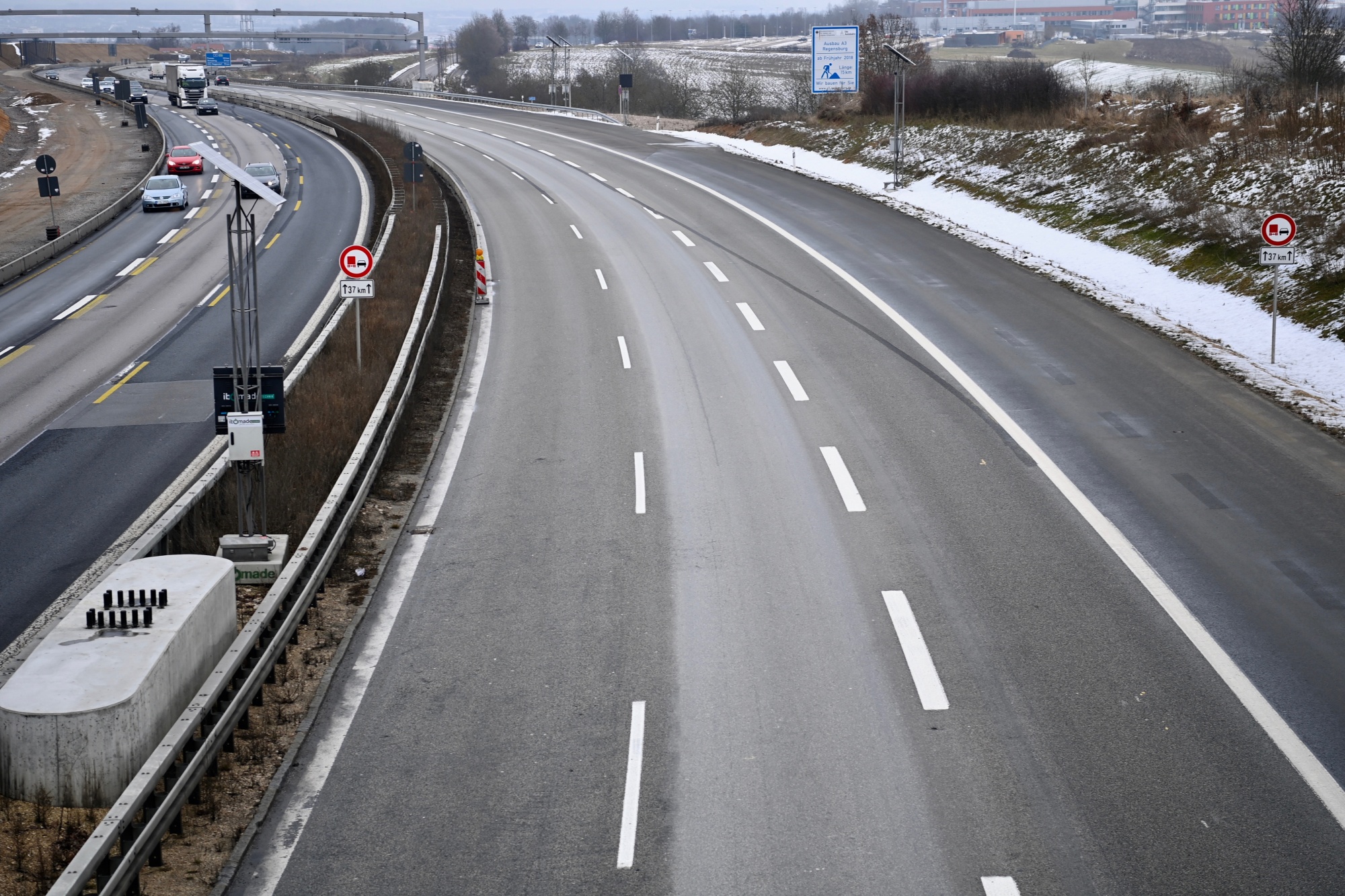 Straßenszene mit Leitplanken und Fahrbahnmarkierungen.