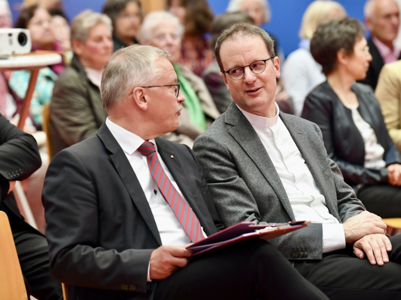 Personen auf St&uuml;hlen h&ouml;ren zu