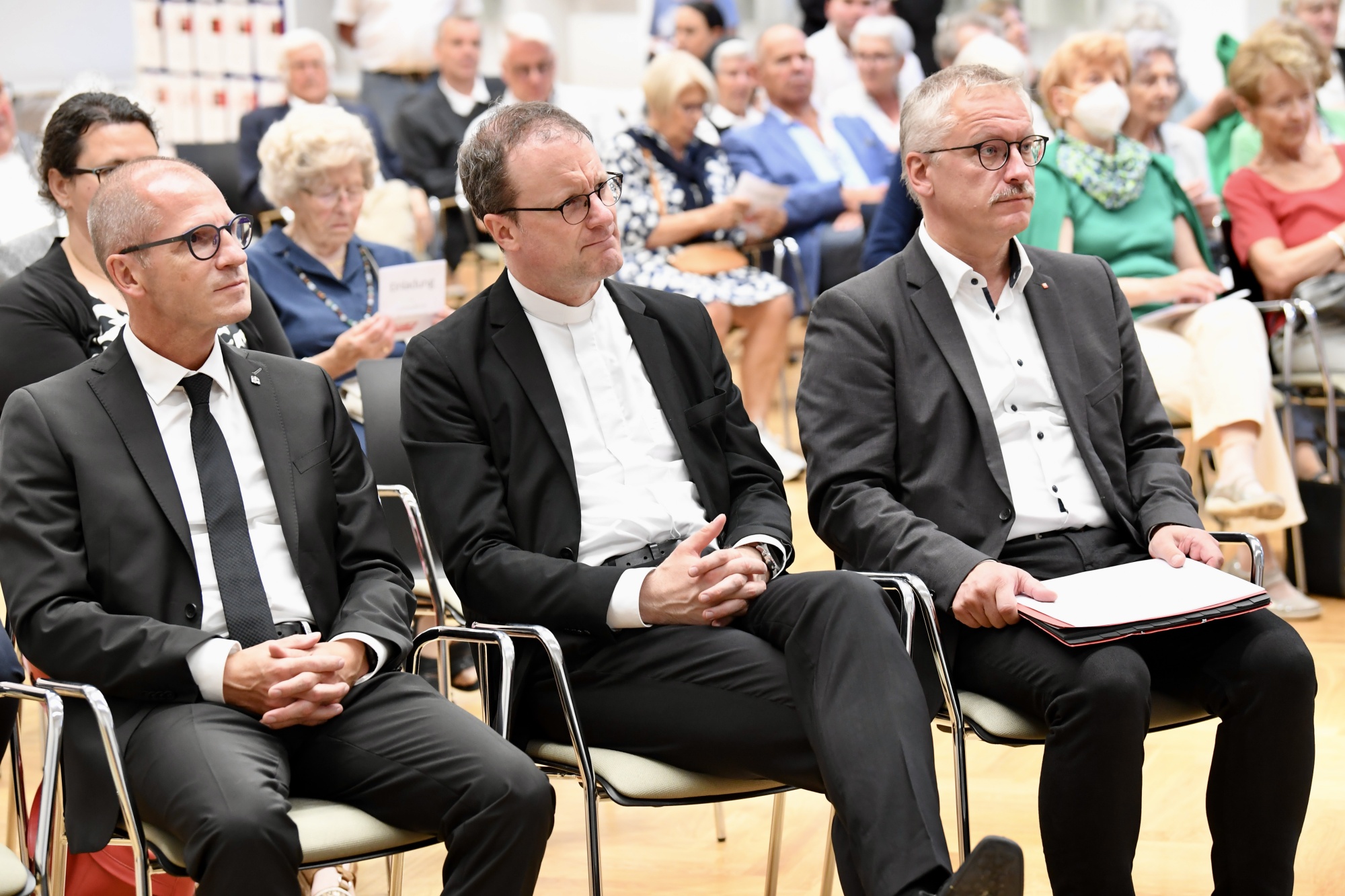 Drei Personen hören einem Vortrag