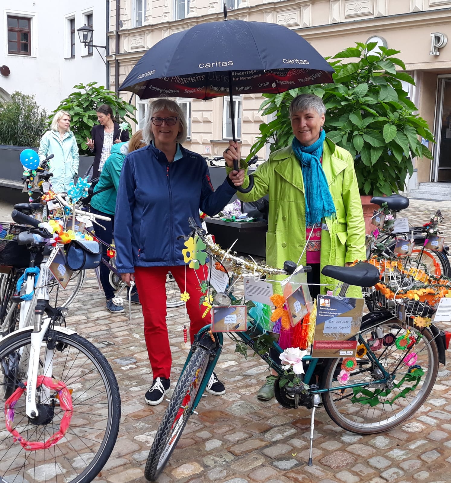 Zwei Personen unter einem Regenschirm hinter Fahrrädern