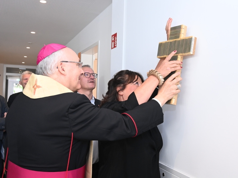 Geistlicher h&auml;ngt Kreuz auf