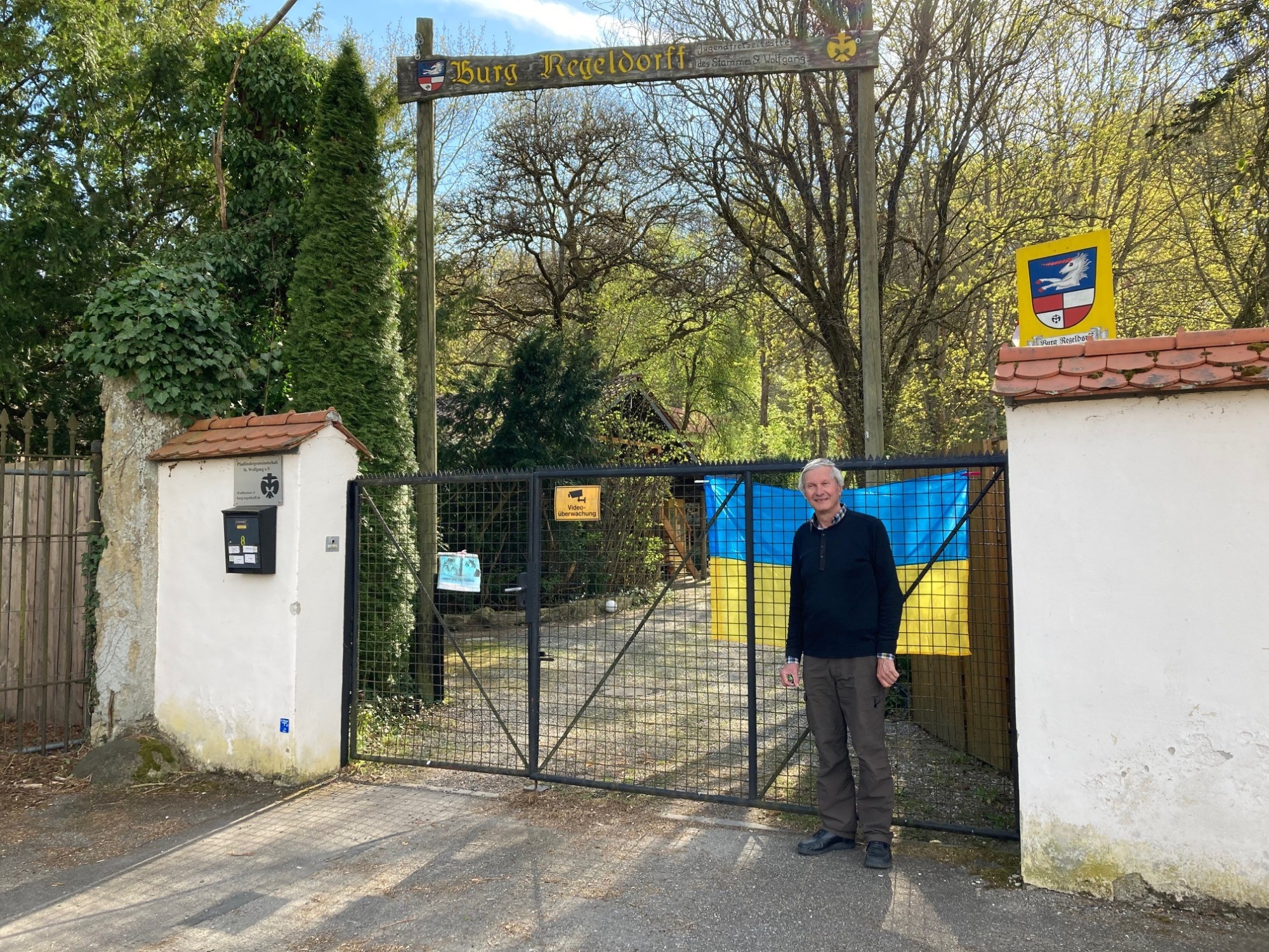 Mann vor Zaun mit Ukraine Fahne