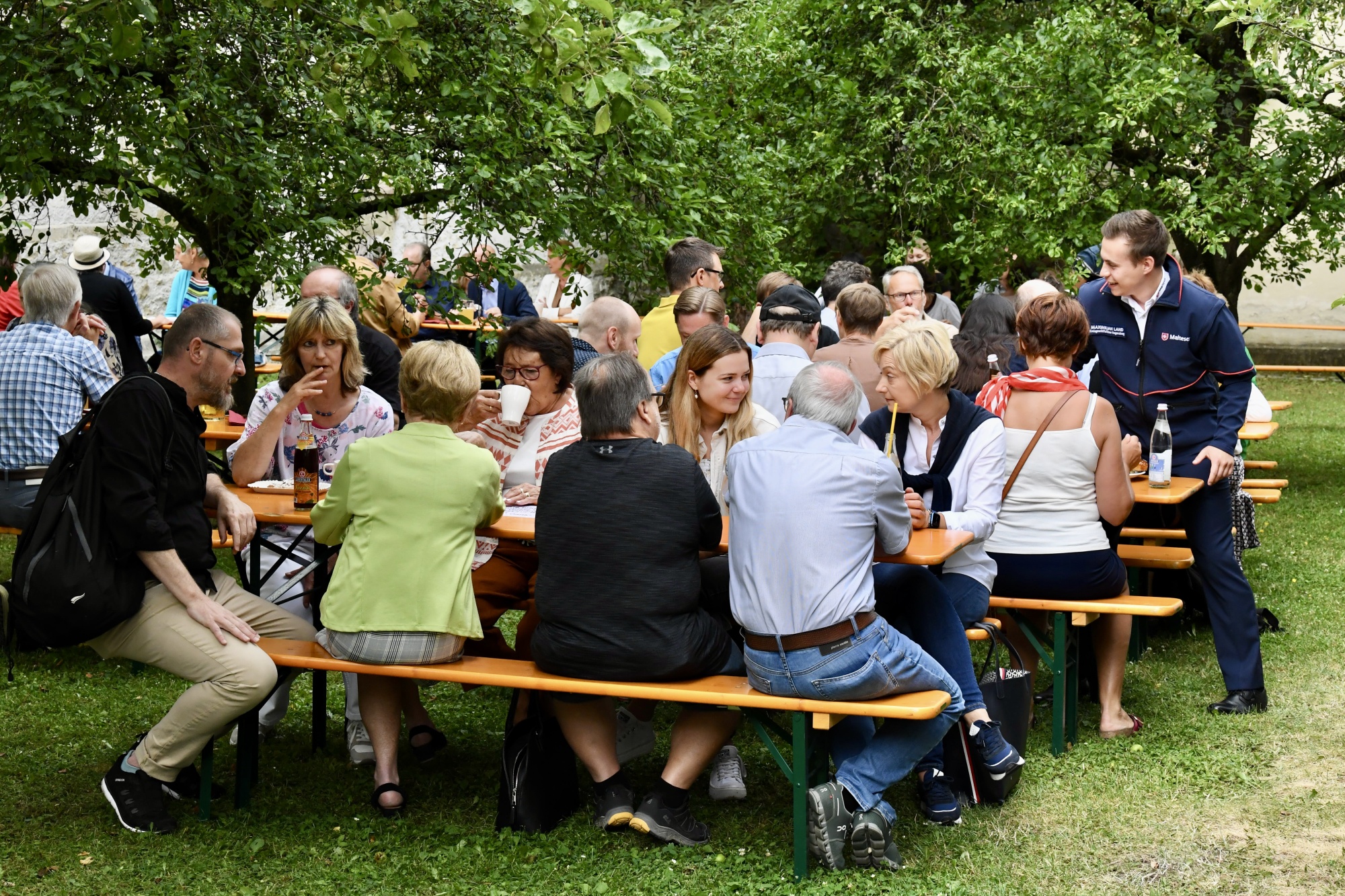 Personen im Garten an Bierbänken