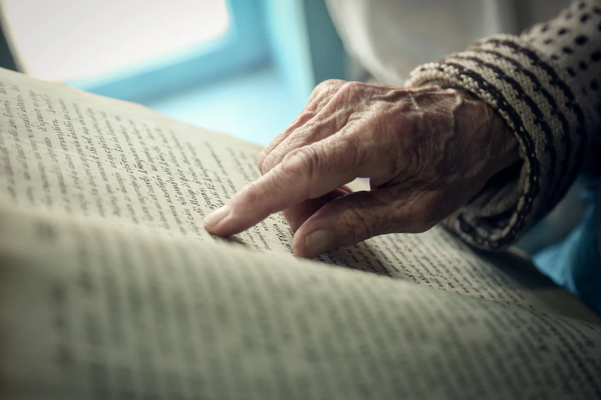 Hand zeigt beim lesen auf Buch