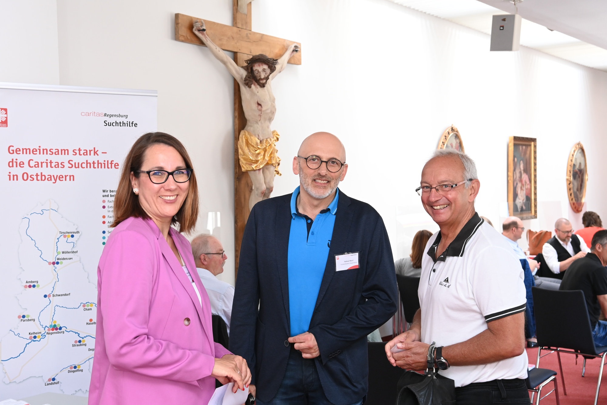 Drei Personen vor Kreuz
