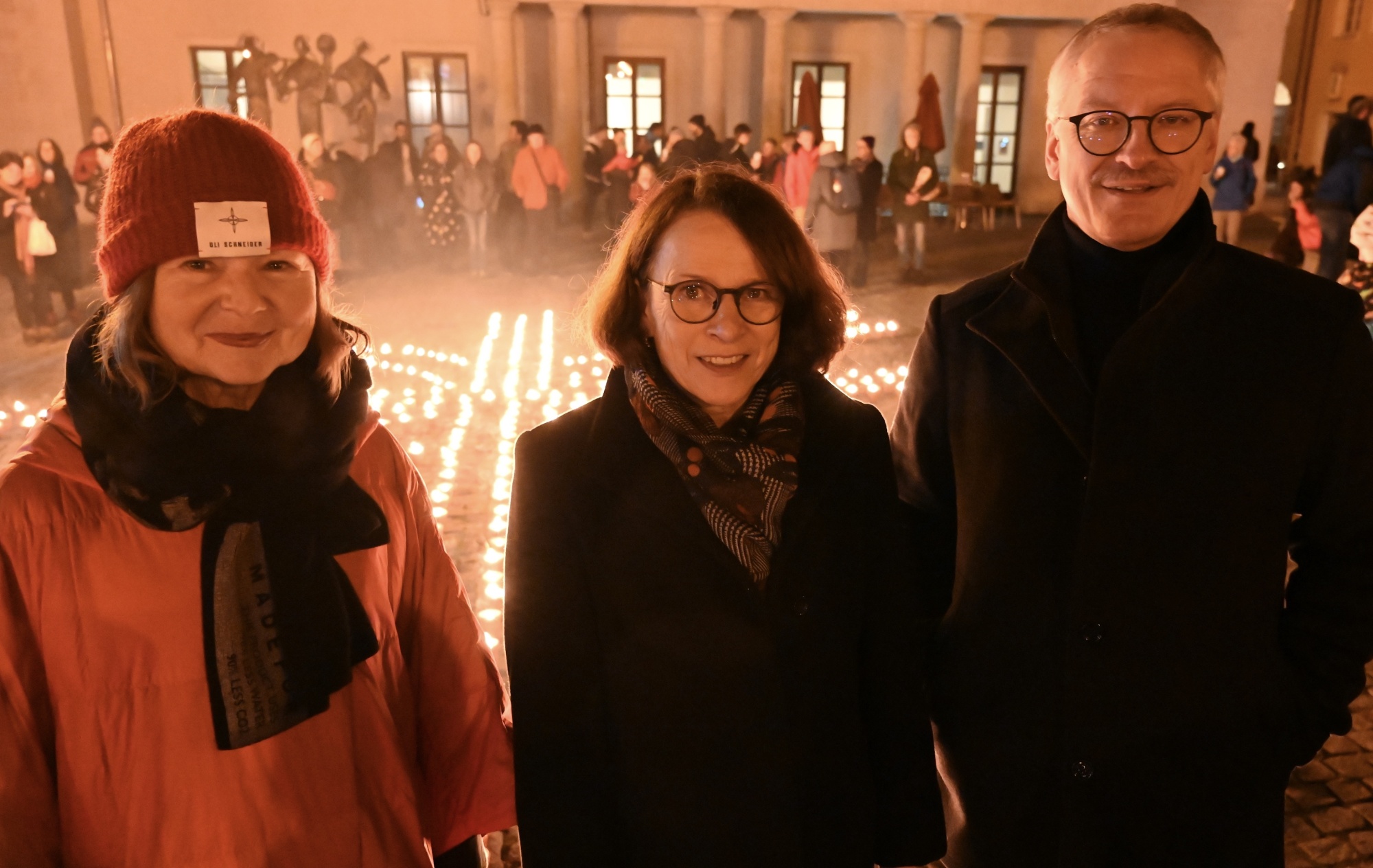 Drei Personen im Portrait vor vielen Kerzen